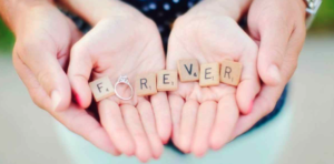 Couple holding Scrabble tiles reading "Forever"