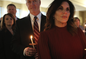 People hold candles at Mass.