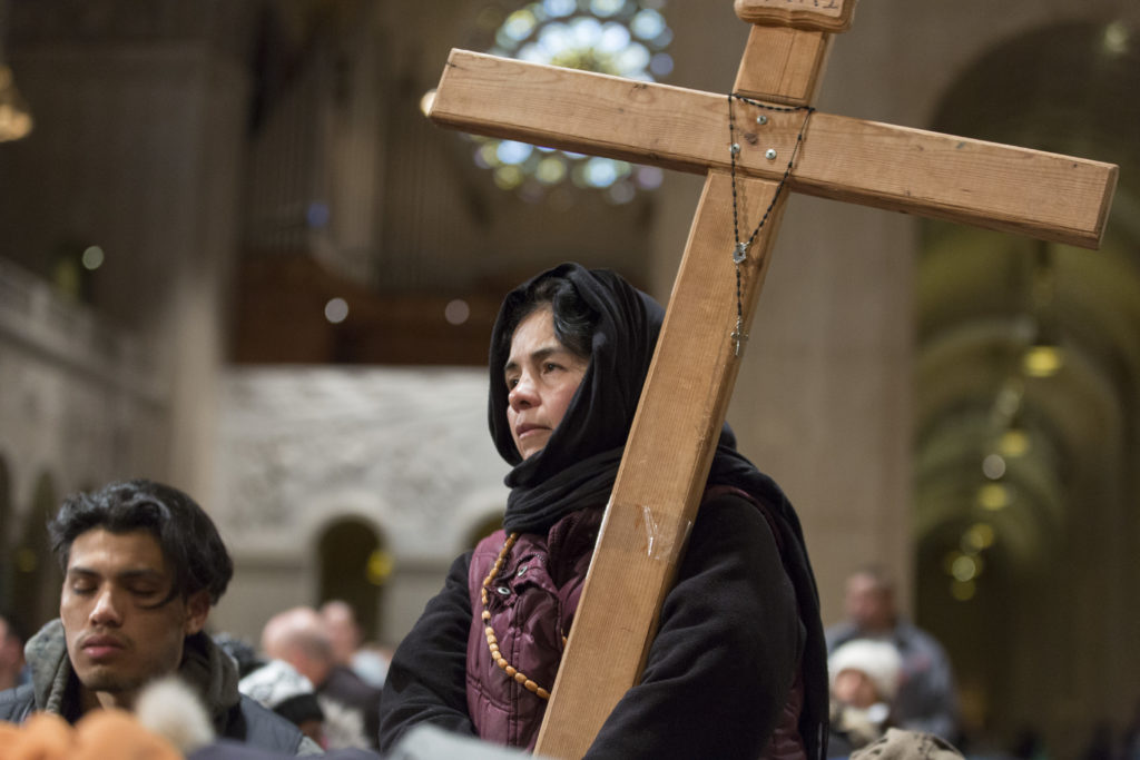 A woman holds a cross.