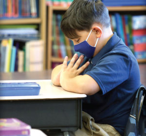 A student prays in the classroom