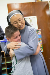 A sister hugs a student
