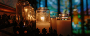 Candles in front of a stained glass window.