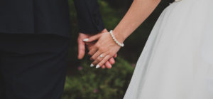 Married couple holding hands at wedding; ring