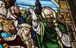 Stained glass window imagery of St. Patrick holding a clover