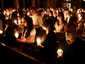 People hold lit candles at the Easter Vigil