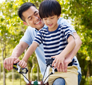 Man helping child on bicycle