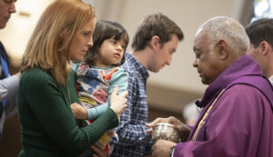 Communion to a mother holding a toddler