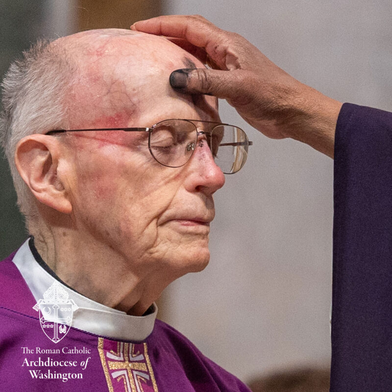 Ash Wednesday priest receiving Ash Cross on forehead.