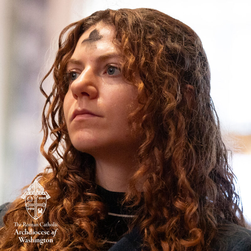 Ash Wednesday Woman looking on toward Altar during Mass. Woman has Ash cross on forehead.